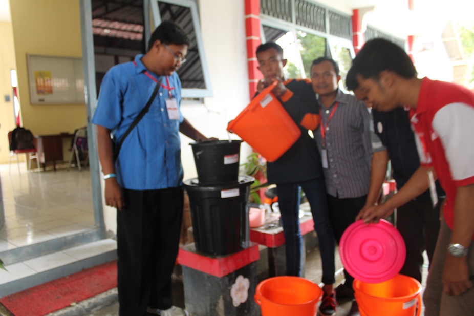 Relawan sedang membuat alat penjernih air biosen dari ember. (foto: Humas)